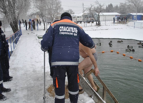 Спасатель помогает во время купания на Крещение
